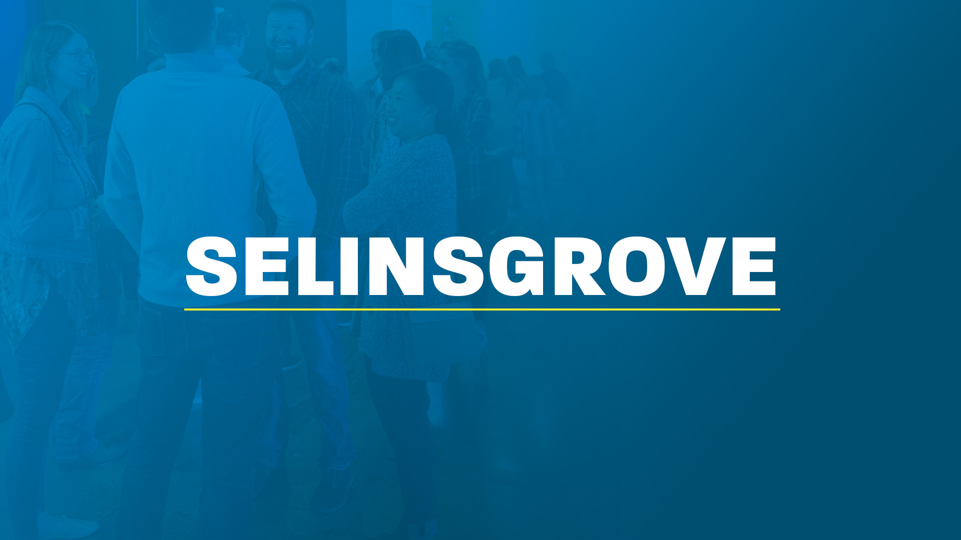 Four young people smiling together in front of the words ‘Penn State,’ written in white and underlined in yellow